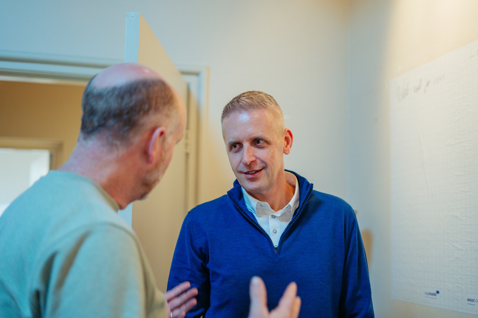 Martijn Messemaker in gesprek met een directeur in een werkkamer